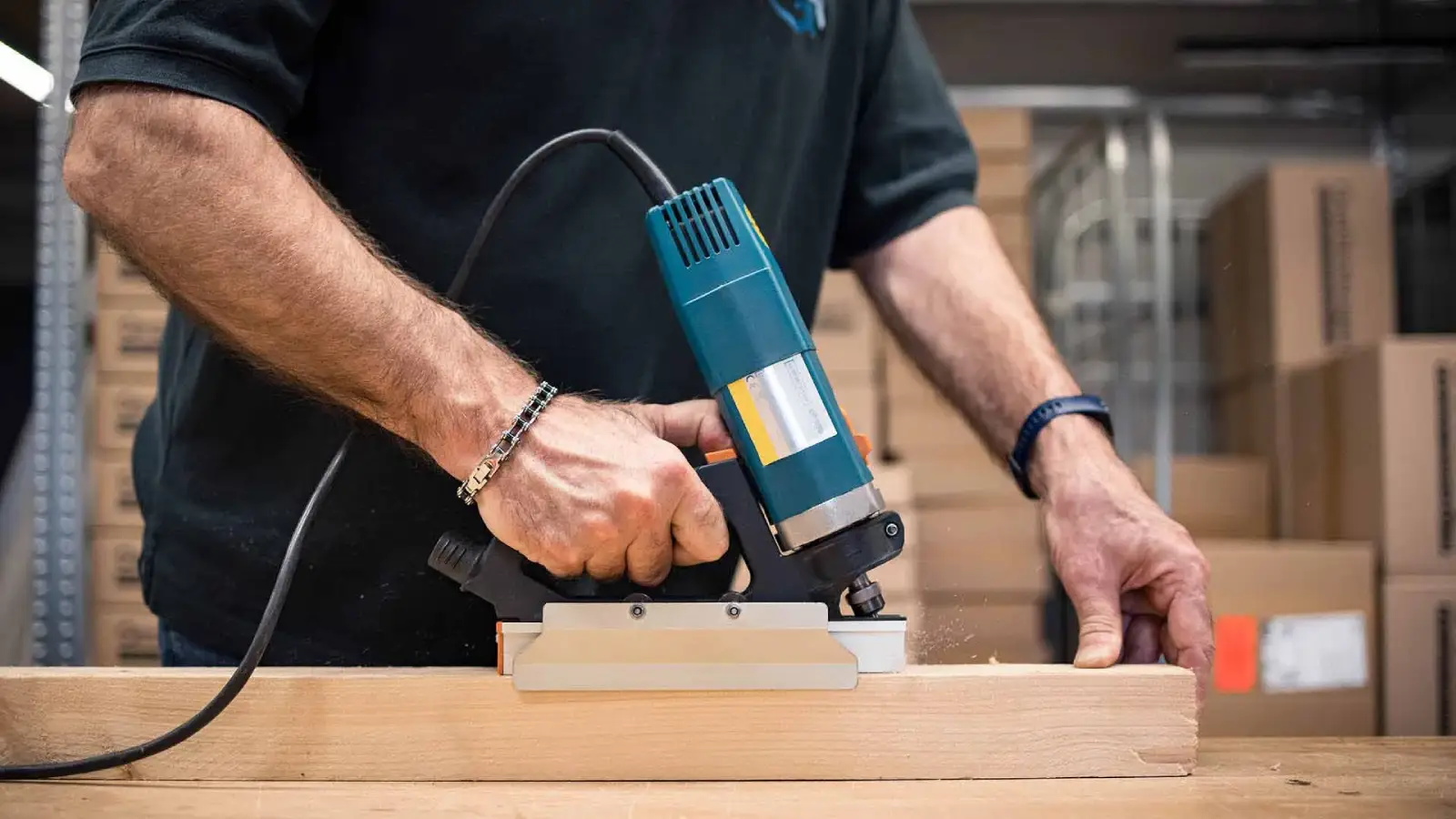 Fräsmaschine in Aktion Person fräst eine Metalleiste auf ein Holzbalken mit einer Fräsmaschine