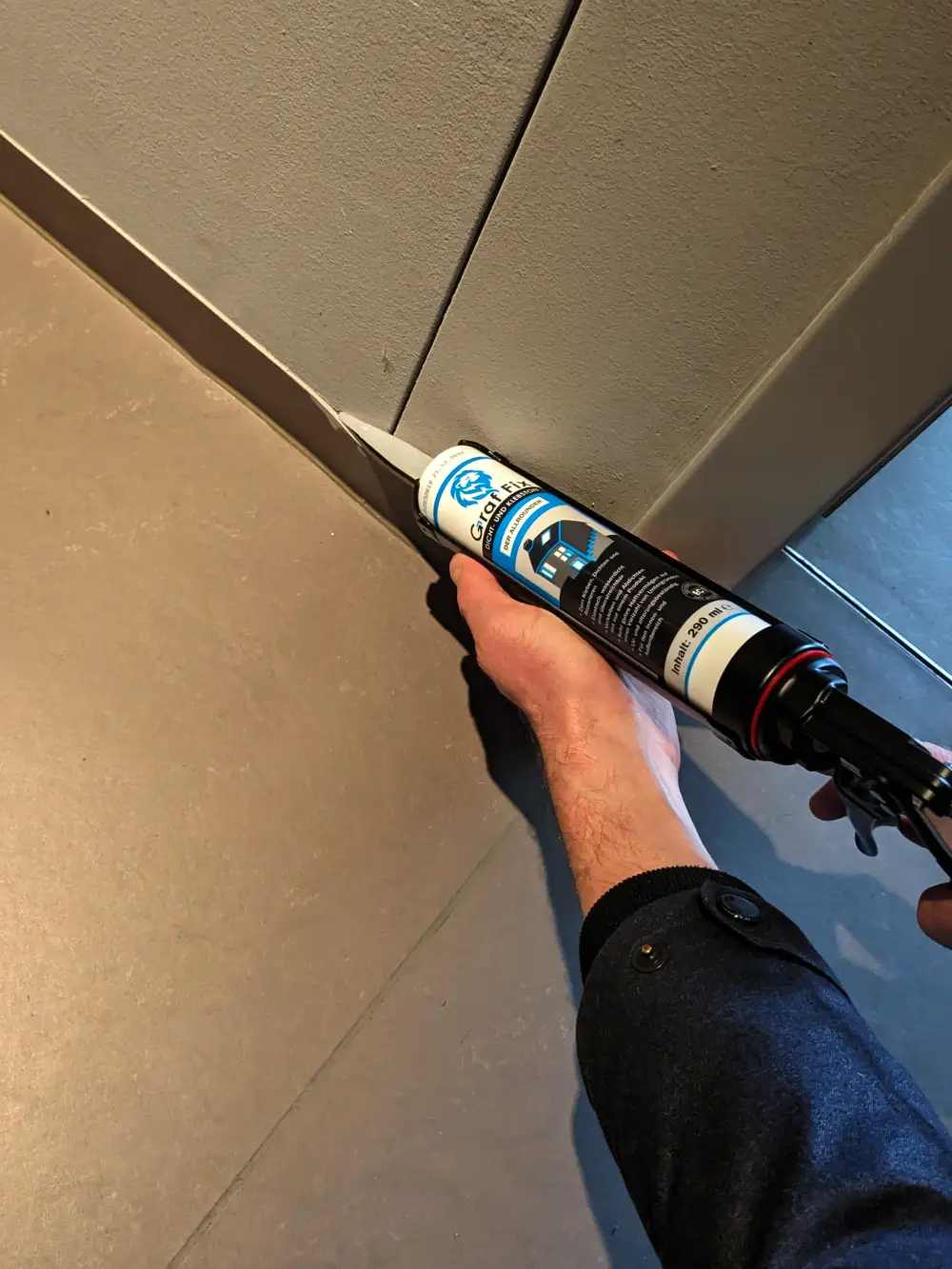 Person benutzt den Graf Fix Dicht- und Klebstoff bei Bodenleisten