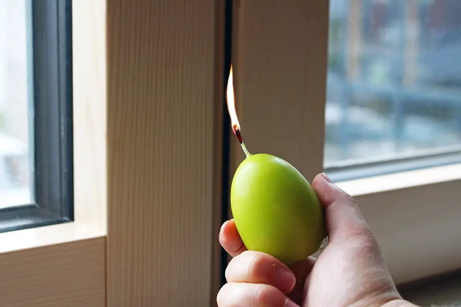 Es wird auf Zugluft geprüft durch die Fensterdichtung mit einer Kerze