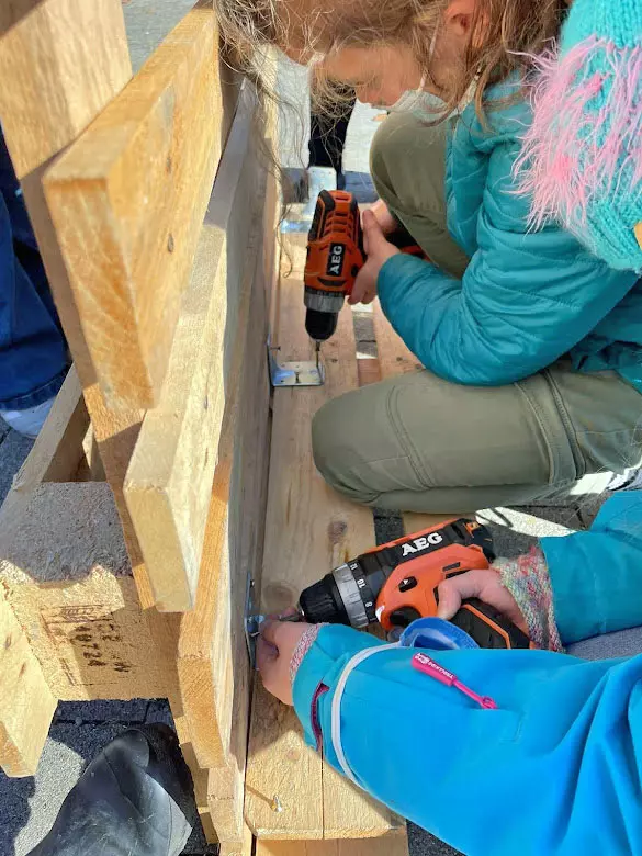 Kinder bauen Palleten zusammen mit Bohrmaschine