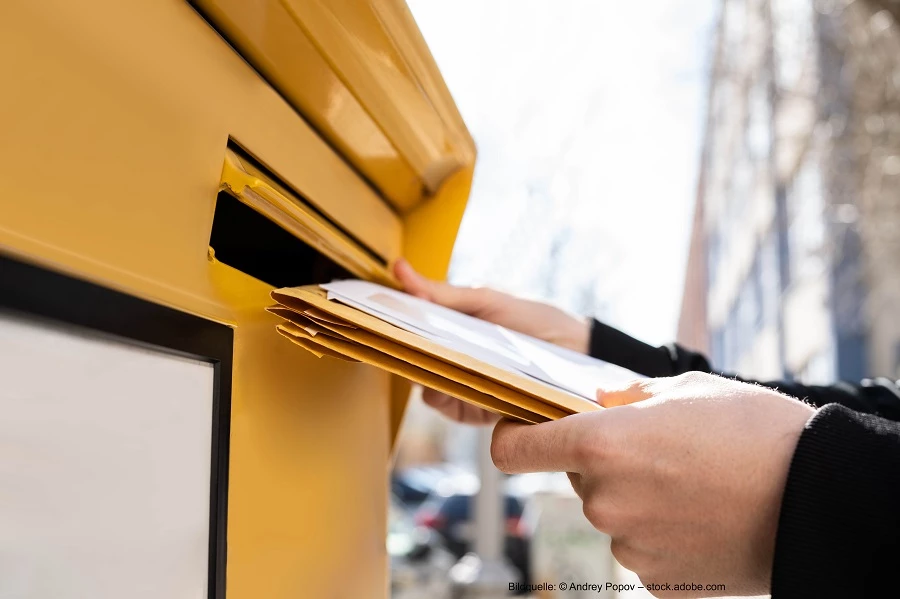 Person wirft Briefe in den Briefkasten