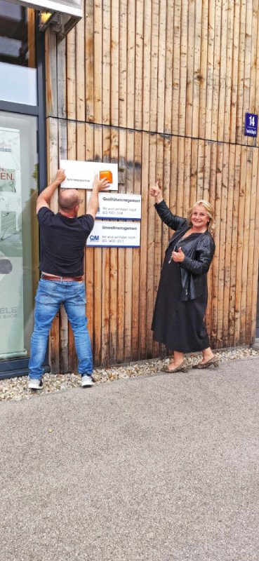 Schreinerpartner Schild wird von 2 Personen auf die Holzwand montiert