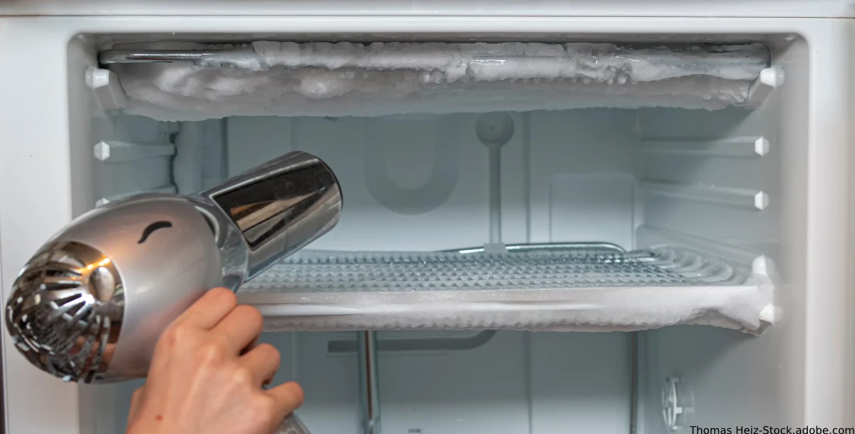 große Eisschicht im Kuelschrank wird mit einem Fön aufgetaut